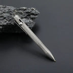 Stonewashed titanium bolt action pen with the writing tip extended against a dark background